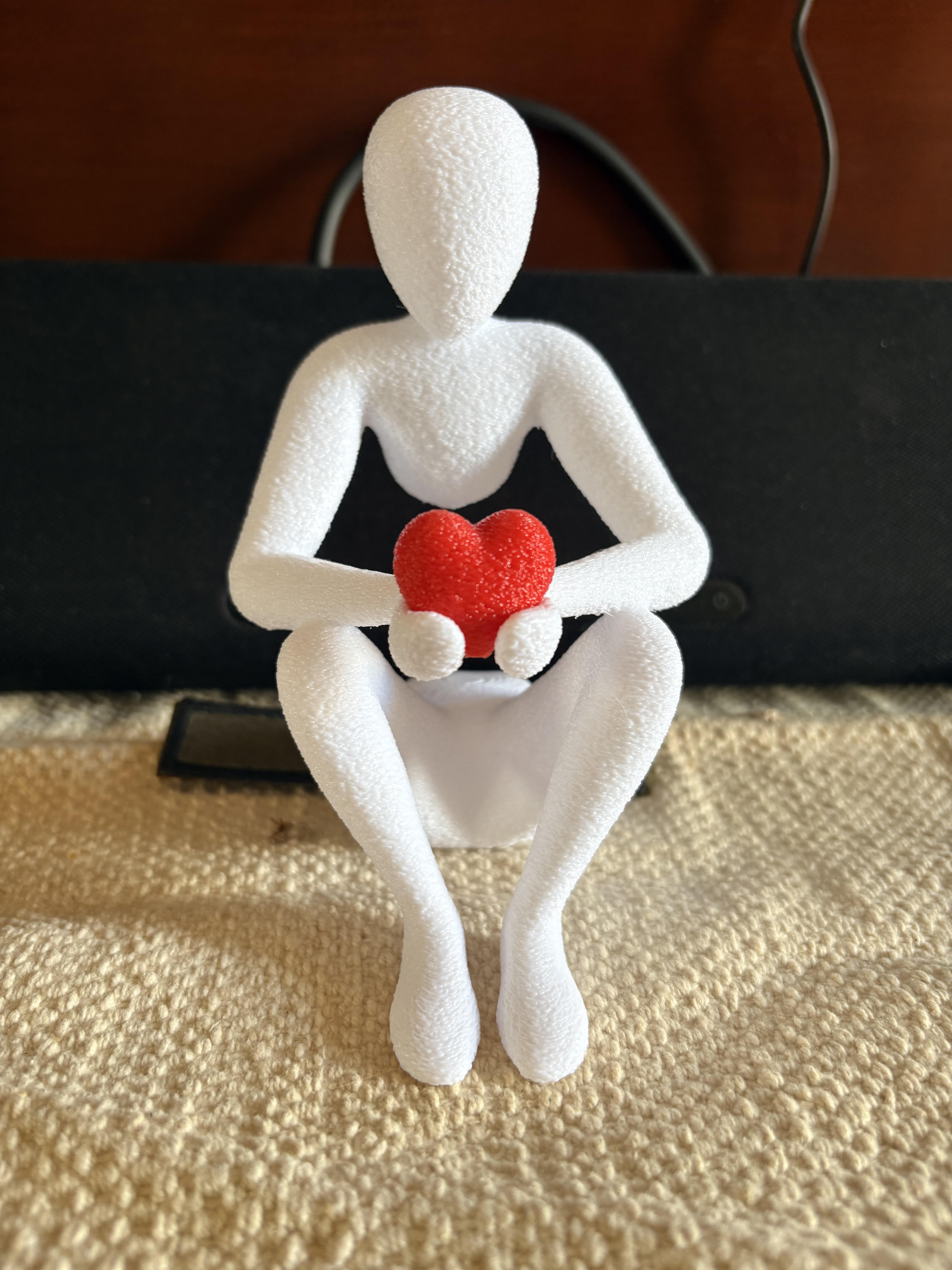 A handmade figure holding a red heart